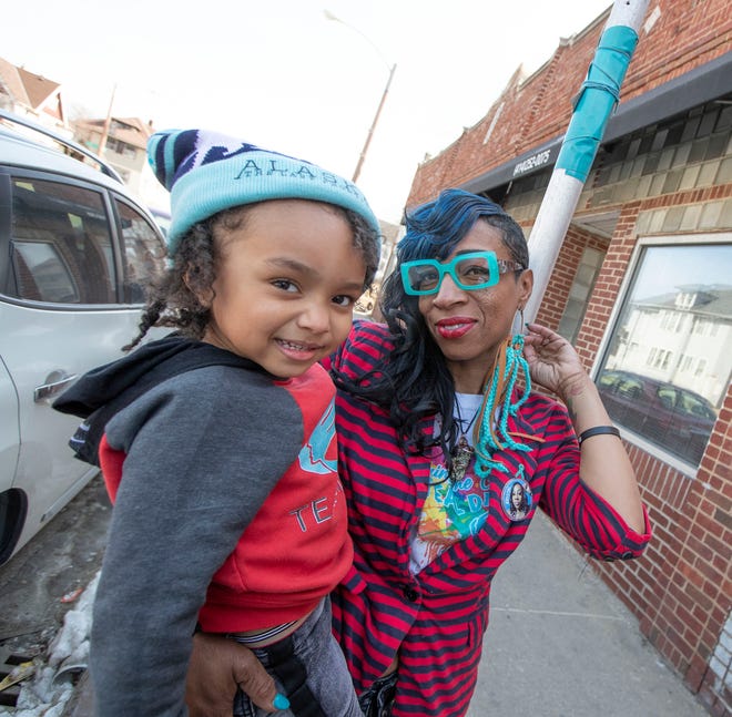 Samantha Collier, the founder of TeamTeal365, which supports survivors of sexual violence, with her 3-year-old son Afrika J. Collier, stands under one of the teal markers outside of The Asha Project, for Paint the City Teal Day in Milwaukee on Thursday, March 10, 2022.