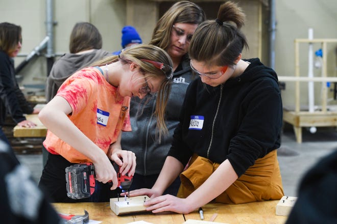 Kara Peterson of G&H Distributing watches as Lydia Schumacher and Kalisa Kraft help each other use a power drill during a field trip for area eighth grade girls to learn about the construction industry on Thursday, March 10, 2022, at the Career and Technical Education Academy in Sioux Falls.
