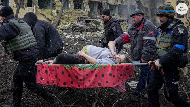 Ukrainian emergency employees and volunteers carry an injured pregnant woman from a maternity hospital that was damaged by shelling.  The woman and the baby died.