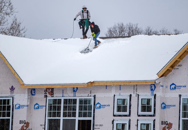 Roofers work to clear snow from atop the Bantry Quarters Townhomes construction on Friday, March 11, 2022, in South Bend. 