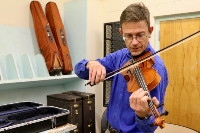 Lyman Bushkovski, instrumental music teacher at Pueblo Academy of Arts, plays a violin the school received from the Bringing Music to Life Instrument Drive.
