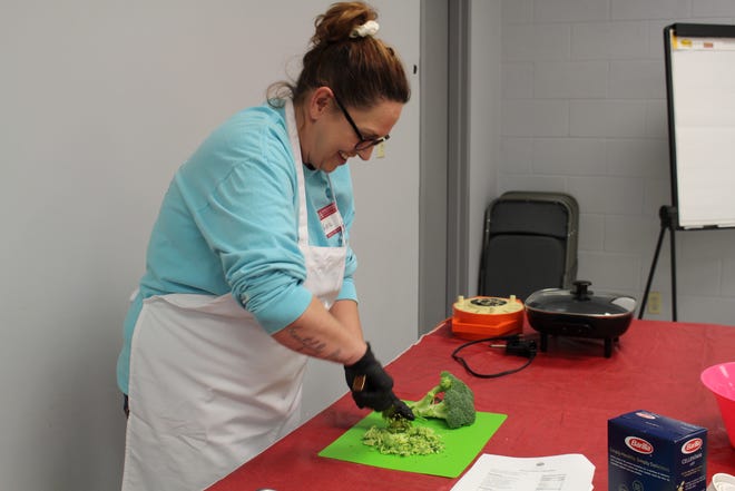 Kenna, a participant in the Cooking Arkansas class in Van Buren, cuts up broccoli for her group's winter Italian vegetable dish on March 10, 2022.