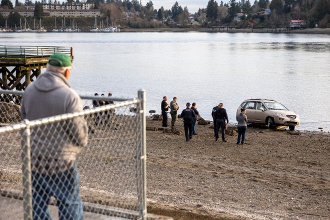 Onlookers watch at Lions Park in Bremerton as a tow truck pulls a vehicle out from the water.
