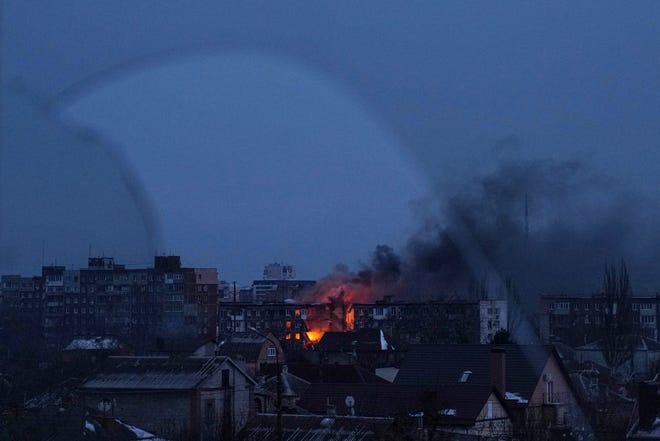 Terlihat melalui jendela yang pecah, api berkobar di sebuah gedung apartemen setelah penembakan sebuah distrik perumahan di Mariupol, Ukraina, Jumat, 11 Maret 2022.