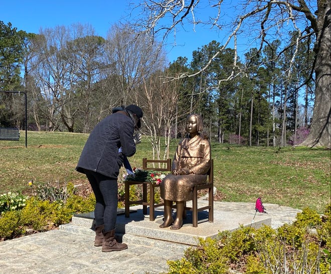 Am 12. März platziert eine Frau eine Rose und ehrt das Georgia Peace Monument, das die mehr als 200.000 Mädchen und Frauen ehrt, bekannt als 