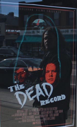 Nate Thompson’s reflection is captured in glass as he looks at the movie poster promoting the premiere of his latest horror film, “The Dead Record.” The movie debuts April 2 at the River Raisin Centre for the Arts. Provided by Reese Bowling