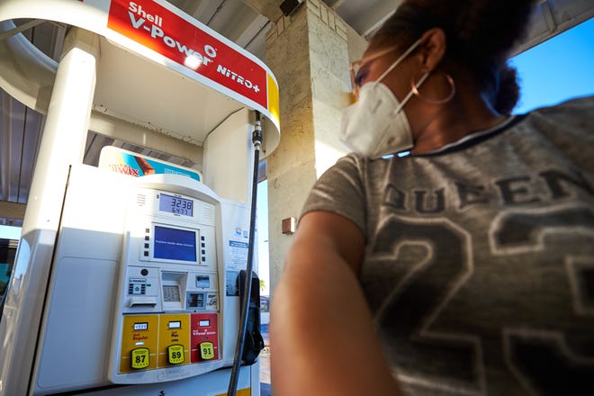 Chiffon Valentine watches the gas pump while filling up her car at the Shell gas station on Scottsdale Road and Weber Drive on March 13, 2022, in Tempe, Arizona.