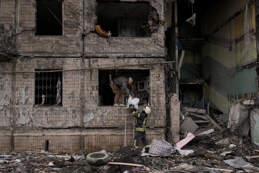 People retrieve belongings from an apartment in a block which was destroyed by an artillery strike in Kyiv, Ukraine, Monday, March 14, 2022.