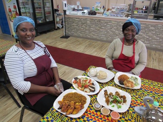 Evelyn Owusu (left) and Elna Saka display several of the Ghanaian dishes served at Elnas African Delights, 6116 Huntley Road in Columbus. Saka opened the restaurant earlier this year.