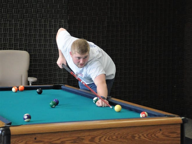 Rhett Talbert, a senior in the Sport and Lifestyle Studies program and president of the Sport and Rec Club, shoots pool in the new Sport and Rec Room at Ohio University Zanesville. The idea for the room came from members of the club, a story organization made up primarily of majors in the SLS program. The club members were looking for a place to call their own and were excited to convert a room formerly used by the Electronic Media program, which has been sound proofed due to media production. The room, which officially opened on Tuesday, is decorated with OUZ Tracer memorabilia and features a pool table, cornhole boards, a mini basketball hoop and a variety of games. Talbert was instrumental in putting this project together.