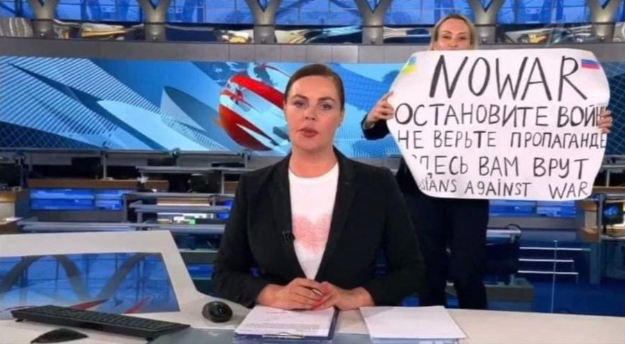 This video grab taken on March 15, 2022 shows Russian Channel One editor Marina Ovsyannikova holds a poster reading " Stop the war. Don't believe the propaganda. Here they are lying to you"  during on-air TV studio by news anchor Yekaterina Andreyeva , Russia's most-watched evening news broadcast, in Moscow on March 14, 2022.