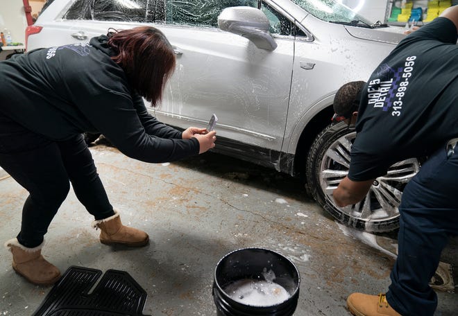 Typhany Jones, 45, of Detroit, left, makes a TikTok video of her son Daviant Palmer, 27, of Detroit as he details cars at her Detroit shop Dae's Detail on Friday, Feb. 25, 2022. 