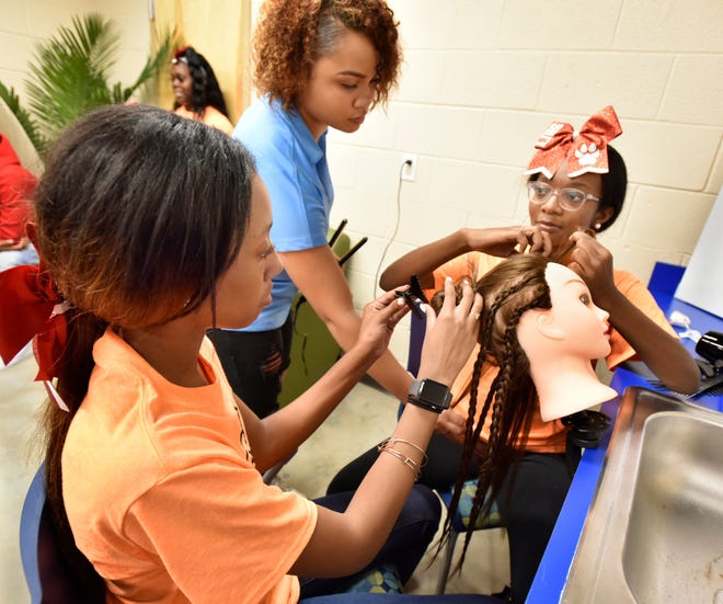 Ja'Miya Brown (left), 15, and Tatiyana Finley (right), 15, work on a hairstyle with the help of staffer Ariyan Herring in the cosmetology salon at the 2019 grand opening of the Boys & Girls Club of Northeast Florida's first stand-alone teen center in Jacksonville.