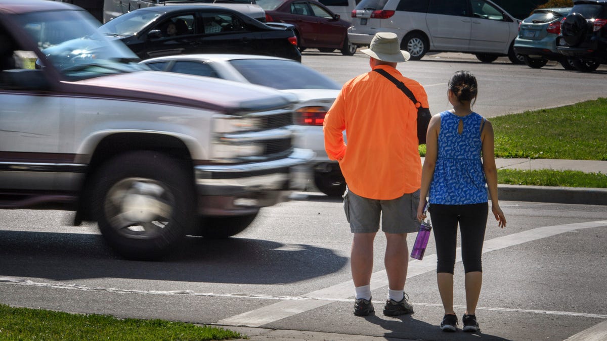 In this June 8, 2016, file photo, a pickup truck drives through the marked crosswalk in front of pedestrian volunteers Dave Passiuk and Nelsie Yang in St. Paul, Minn. Drivers of bigger vehicles such as pickup trucks and SUVs are more likely to hit pedestrians while making turns than drivers of cars, according to a new study.