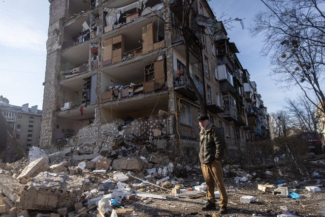 Seorang pria berdiri di tengah puing-puing di depan kompleks apartemen perumahan yang rusak berat akibat serangan Rusia pada 18 Maret 2022 di Kyiv, Ukraina.