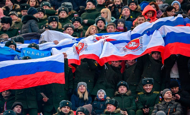 Taruna dan perwira militer Rusia mengibarkan bendera nasional Rusia dan Krimea menghadiri konser yang menandai ulang tahun kedelapan referendum tentang status negara bagian Krimea dan Sevastopol dan penyatuannya kembali dengan Rusia, di Moskow, Rusia, Jumat, 18 Maret 2022.