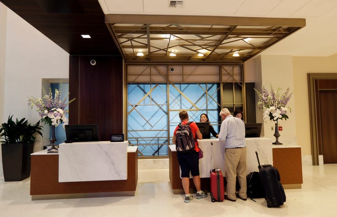 In this 2018 file photo, guests stand at the front desk at the Embassy Suites by Hilton hotel in Seattle's Pioneer Square neighborhood in Seattle.