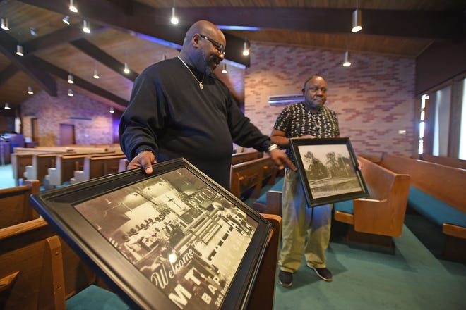 The Rev. Derek Williams, left, and Danny Rucker hold historical images of the 104-year-old church.