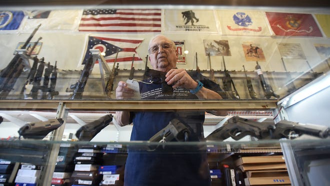 Wally Toward pulls out a Smith & Wesson M&P Shield, one of the more popular concealable hanguns, from the display case at Mansfield Sporting Arms in downtown Mansfield.