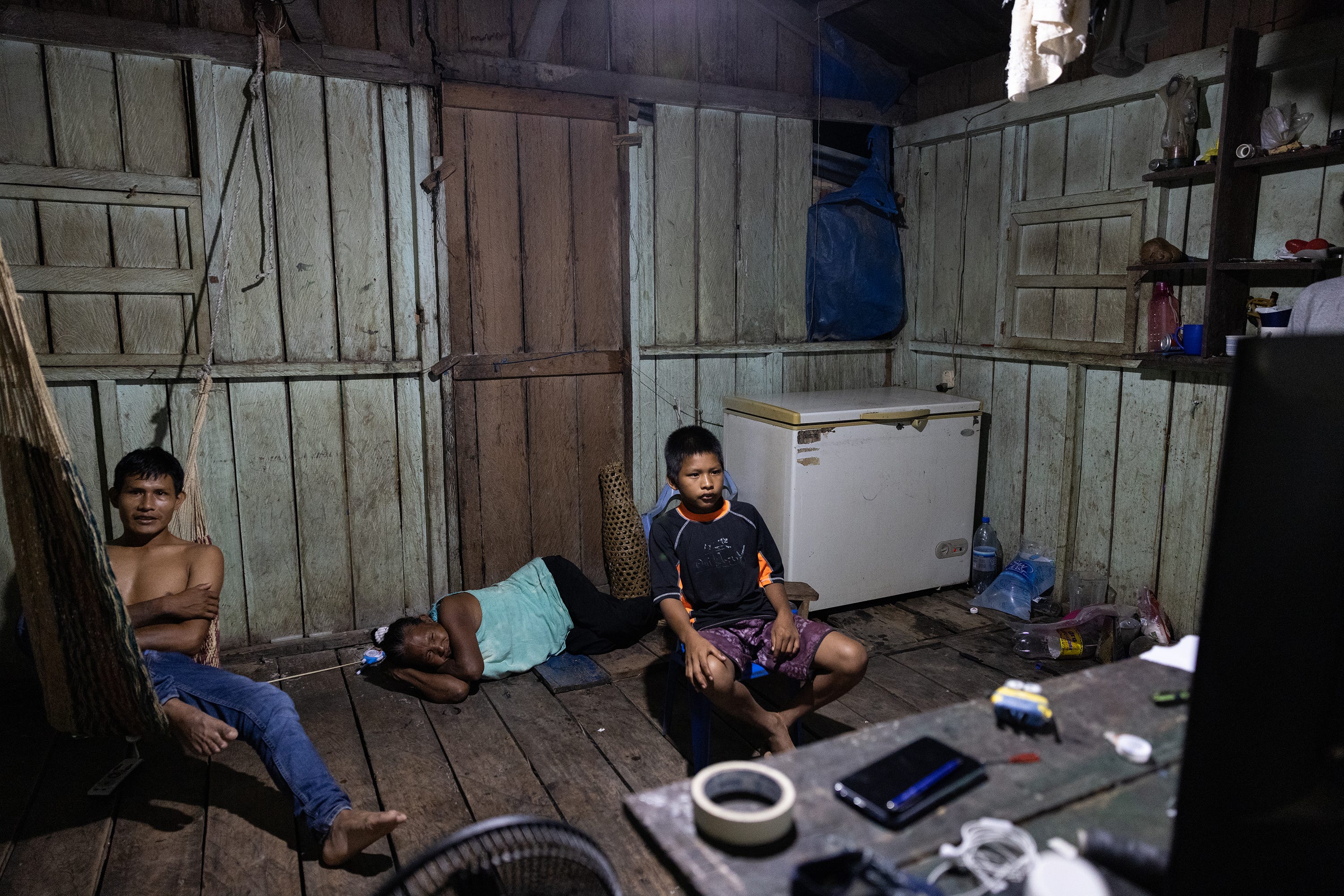 Matilde Fernando Parente and two of her grandchildren rest at night while watching a television program.