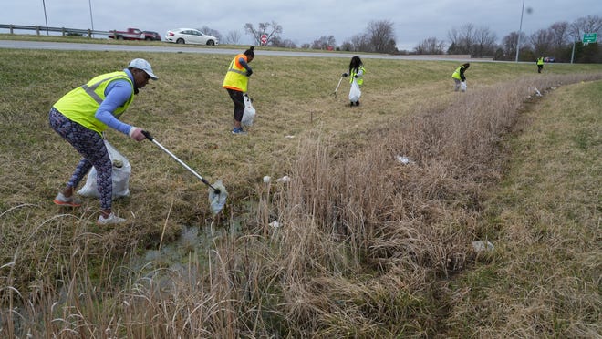 Varsey Laurelle, left, lifts water-soaked trash out of a ditch at the James Road and I-70 interchange. Beside her are, from left, relatives Cheralee Calhoun, Alex Hinton and Janice Hinton. They are among the volunteers who showed up Saturday as part of the litter collection effort KickButt Columbus!