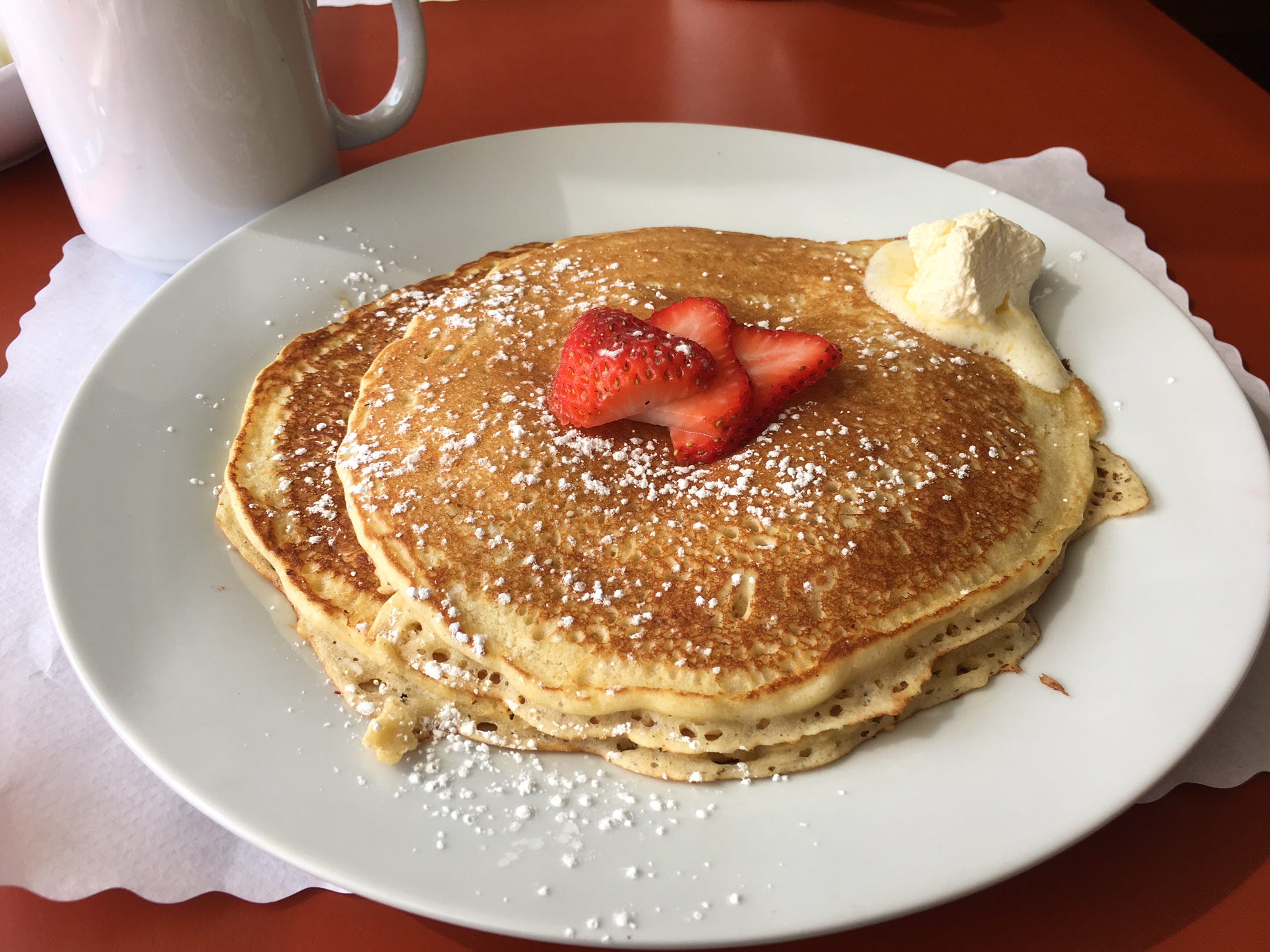 plate of three pancakes wth melting butter and whipped cream