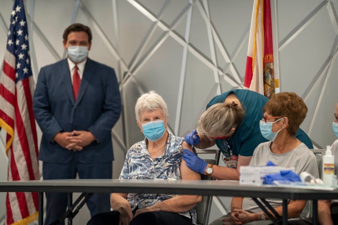 Govt.  Ron DeSantis watches Jessica Brown, 77, receive the Moderna COVID-19 vaccine from nurse Sherry Phillips in this 2020 photo at the Kings Point clubhouse in Delray Beach.