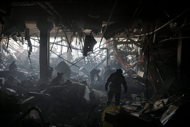 Petugas pemadam kebakaran dan prajurit Ukraina mencari orang-orang di bawah puing-puing di dalam pusat perbelanjaan setelah pemboman di Kyiv, Ukraina, Senin, 21 Maret 2022.