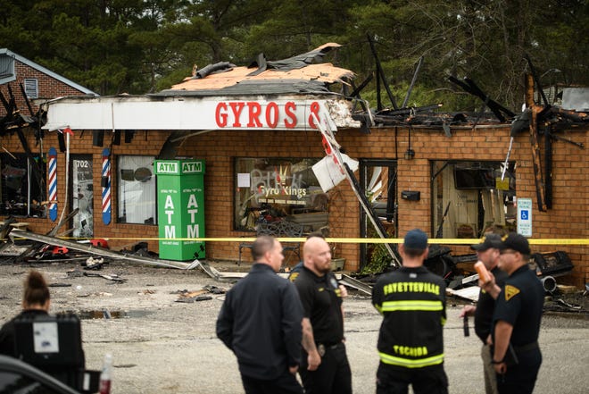 Firefighters and police officers stand outside Gyro Kings restaurant and ACC Sports Cuts barbershop on the 700 block of N. Reilly Road which were destroyed in a fire on Wednesday, March 23, 2022.