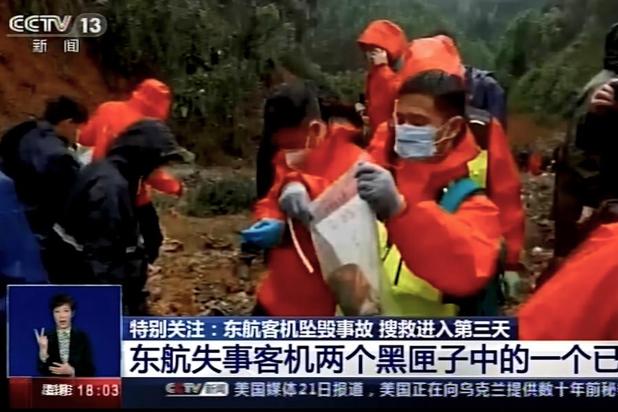In this image taken from video footage run by China's CCTV, an emergency worker puts an orange-colored "black box" recorder into a plastic bag at the China Eastern flight crash site Wednesday, March 23, 2022, in Tengxian County in southern China's Guangxi Zhuang Autonomous Region.