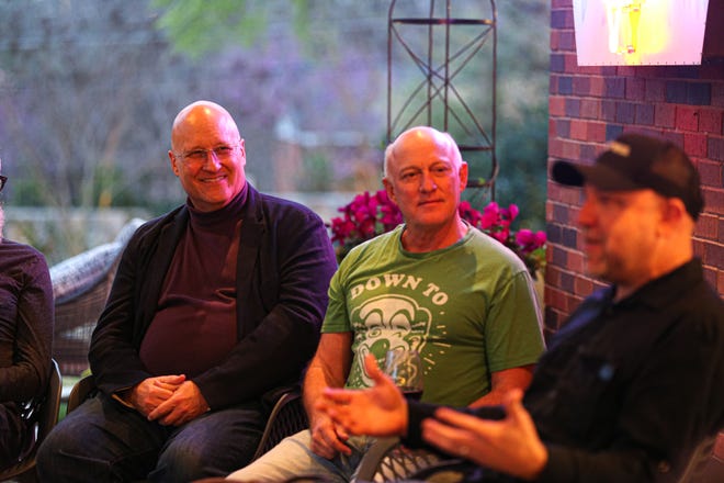 Paul Normandin, from left, and Bill Frisbie listen to a story at Frisbie's monthly Drinking with the Saints event on March 17. The series features storytellers from all walks of life speaking on personal experiences without barriers or judgment.