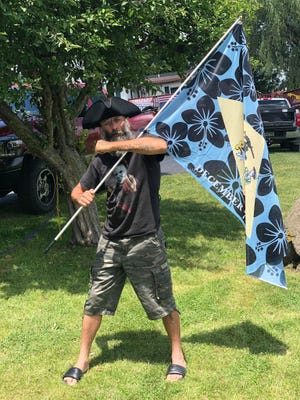 In this photo provided by the U.S. Attorney's Office, Delaware man Barry Croft is pictured in July 2020 carrying a "Boogaloo" flag in Cambria, Wisc.
