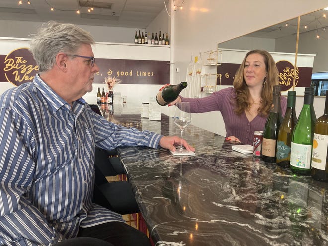 Mickie Meinhardt sirve vino espumoso al cliente Chris Coppinger en su nueva empresa The Buzzed Word.