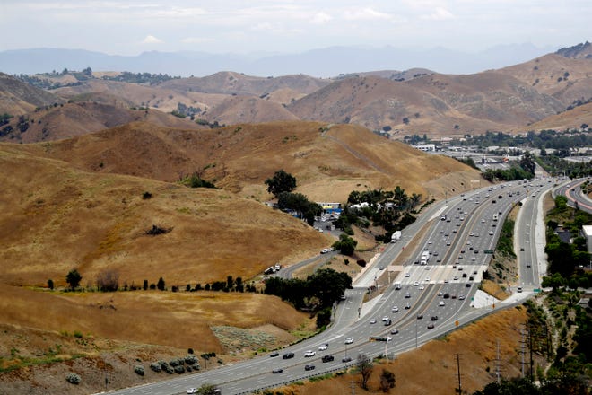FILE - U.S. Highway 101 passes between two separate open space preserves on conservancy lands in the Santa Monica Mountains in Agoura Hills, Calif., July 25, 2019. Groundbreaking is set for next month on what will be the world's largest wildlife crossing, a bridge over a major Southern California highway that will provide more room to roam for mountain lions and other animals hemmed in by urban sprawl. A ceremony marking the start of construction for the span over U.S. 101 near Los Angeles will take place on Earth Day, April 22, the National Wildlife Federation announced on Thursday, March 24, 2022. (AP Photo/Marcio Jose Sanchez, File)