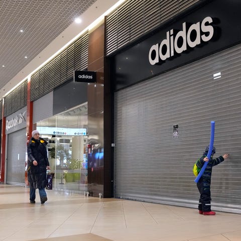 People walk past closed Adidas, Reebok and other s