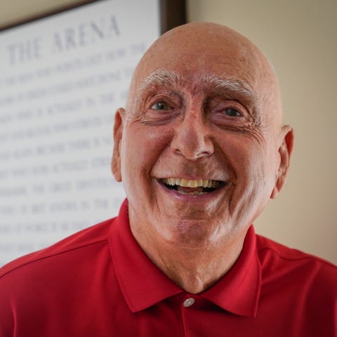 Dick Vitale stands in front of a framed quote from
