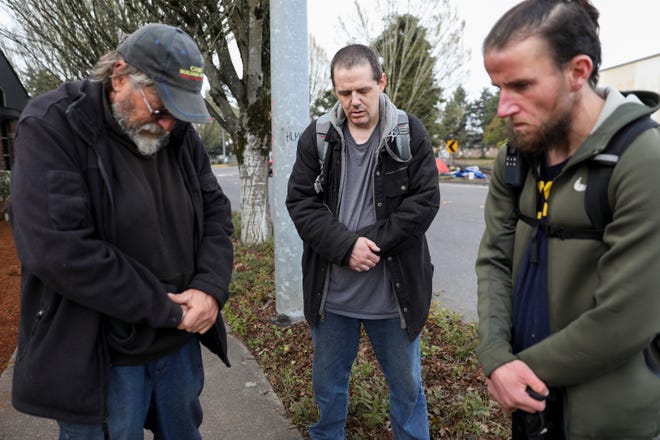 Carl Rhymes, Enoch Gerber and Mike Wade pray for the victims of a car accident that killed four people at a homeless camp near Front Street Northeast on Sunday, March 27, 2022 in Salem, Ore. 