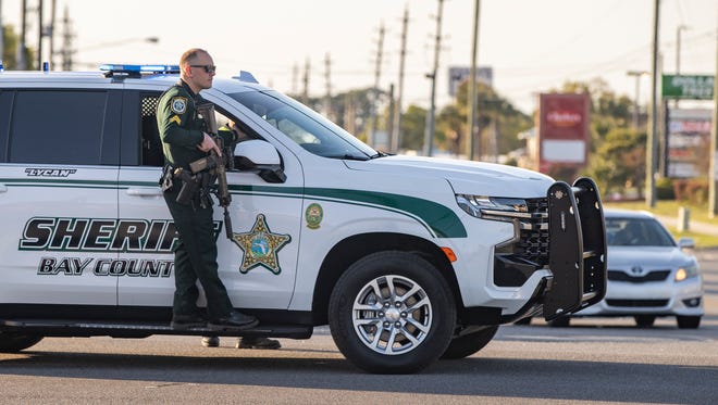 Un oficial de la Oficina del Sheriff del Condado de Bay conduce su rifle frente a un vehículo BCSO a lo largo de Front Beach Road después de un tiroteo el domingo.