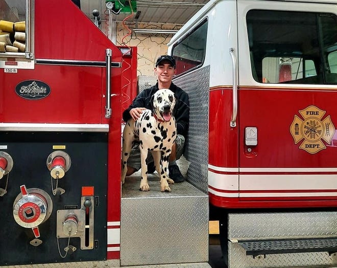 Marshal poses on a truck with is caretaker and handler Logan Rider.