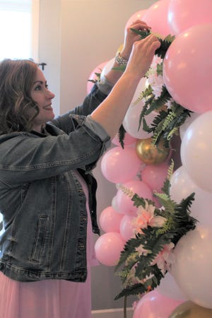 Mindy LaRocca puts the finishing touches on balloon garland she created as part of the decor for a brunch date with friends. She purchased the flowers and ferns from the Dollar Tree. Provided by Kennedy Bowling