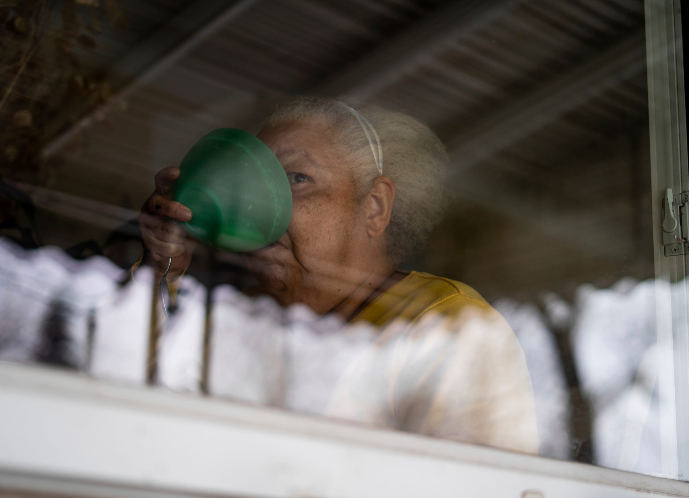 Debra Westbrook drinks the milk from her cereal bowl while staring out the front window in her dining room during a brief break from taking care of her son at her Detroit home in Detroit on Thursday, Feb. 10, 2022. "Marvin will be calling me soon, so I've got to eat up. I haven't changed him yet," said Westbrook. 
