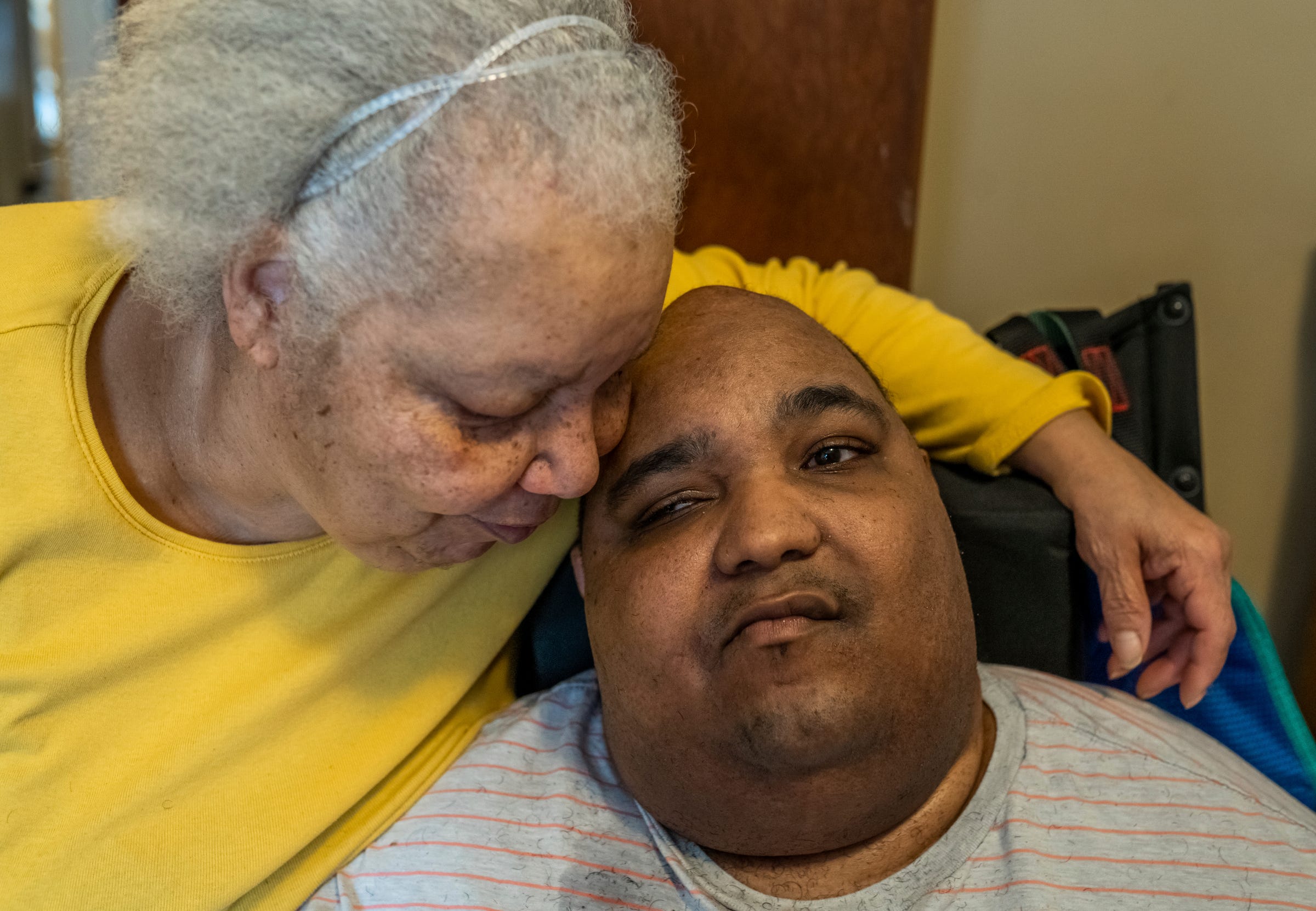 Debra Westbrook, of Detroit, rests her face on her son Marvin McQueen Jr. inside their home in Detroit on Thursday, Feb. 10, 2022. For the past five years, the two of them have been stranded inside their west-side house.