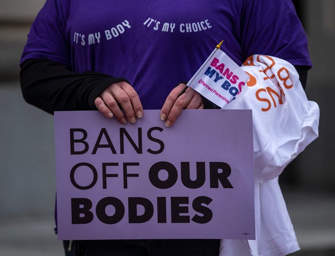 A protester holds a sign in front of the Kentucky State Capitol in Frankfort over House Bill 3, which would restrict abortions in the state. March 29, 2022