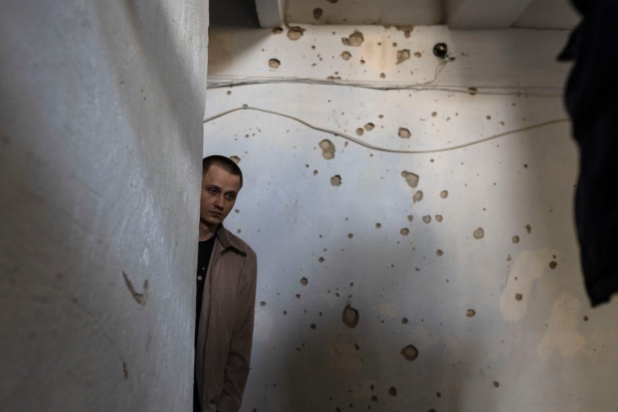 A man stands inside a building in front of a wall damaged from shrapnel following a Russian attack on the previous night, in the residential area of Mikolaiv, Ukraine, on Tuesday.