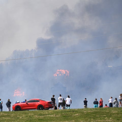 People watch as structures burn off of highway 321