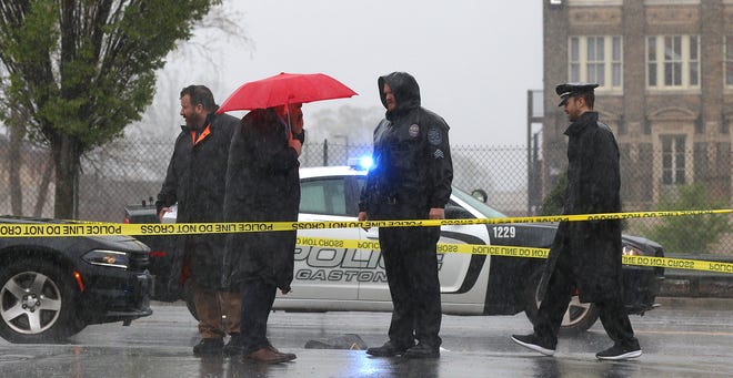 Investigators work in the rain at the scene of a shooting on West Long Avenue at North Falls Street near the Gaston County Courthouse Thursday morning, March 31, 2022.