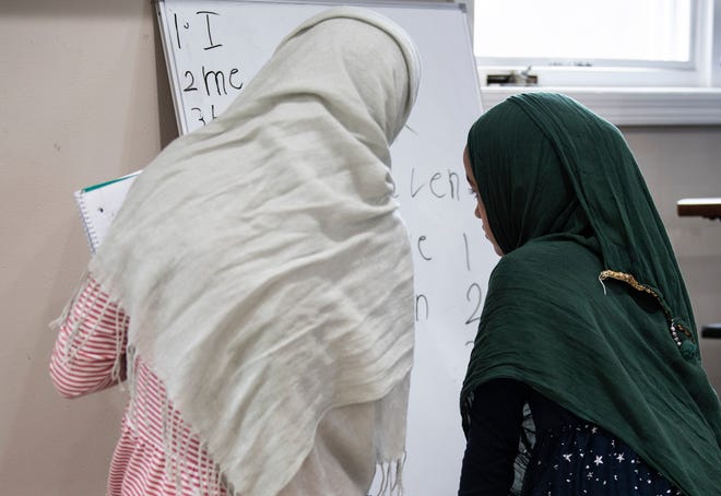 Shabogul Safi, 13, and her sister Samina, 10, work on writing in English together at their temporary home in Urbandale.