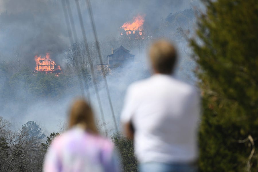 People watch as structures burn from a wildfire Wednesday, March 30, 2022, in Sevierville, Tennessee.
