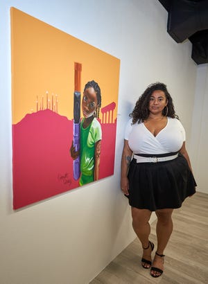 Antoinette Cauley poses for a portrait next to one of her pieces in the Blackbird Fly 2022 gallery at GateWay Community College in Phoenix on April 1, 2022