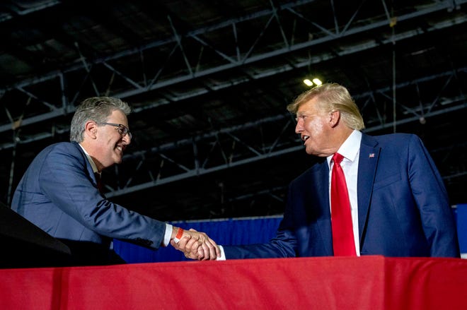Matt DePerno, Candidate for Attorney General of Michigan, left, shakes hands with Former President Donald J. Trump during the Save America Rally at Michigan Stars Sport Center in Washington Township, Mich. on April 2, 2022.